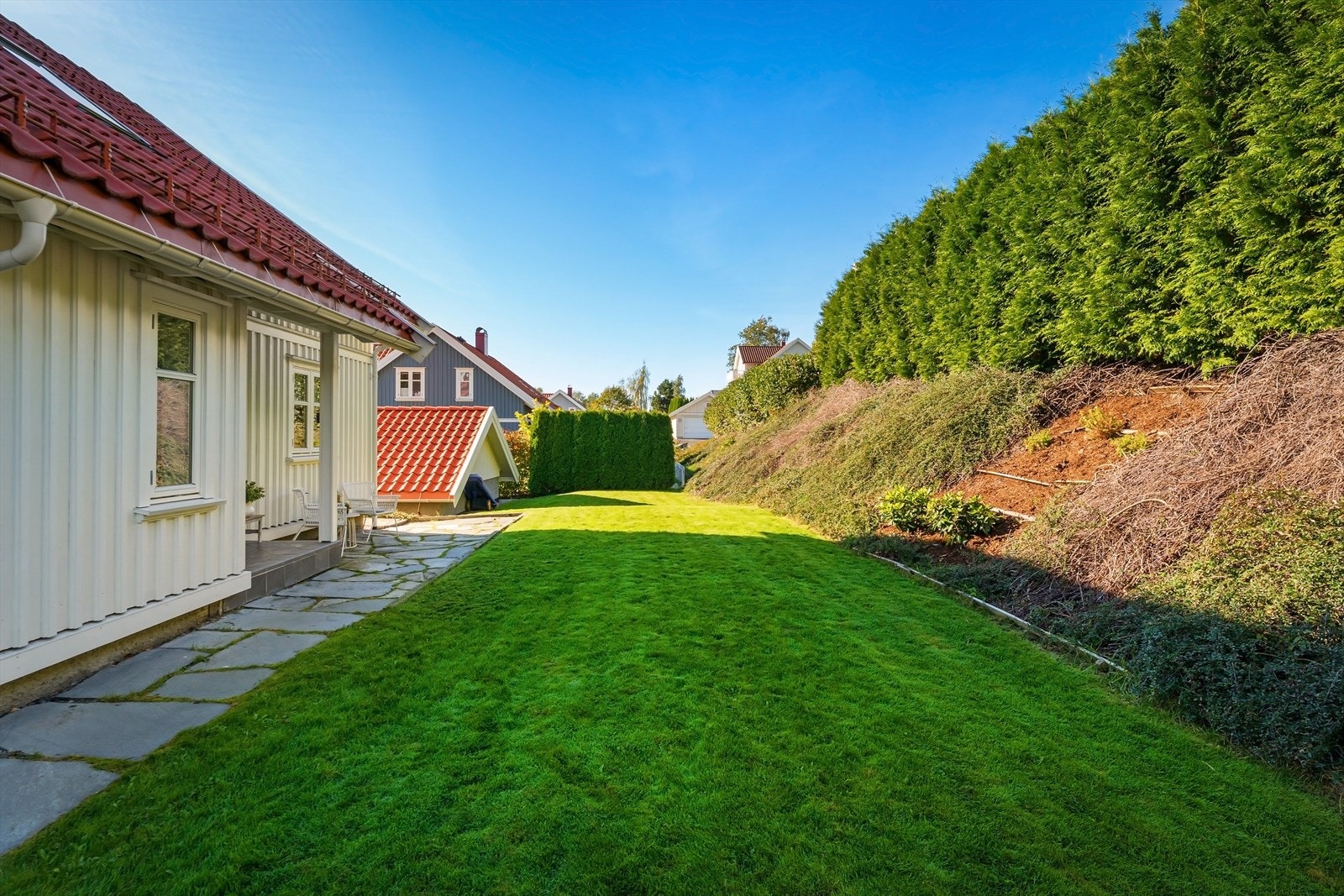 Tomten er pent opparbeidet med prydbusker og skjermende beplantninger. Galleribilde