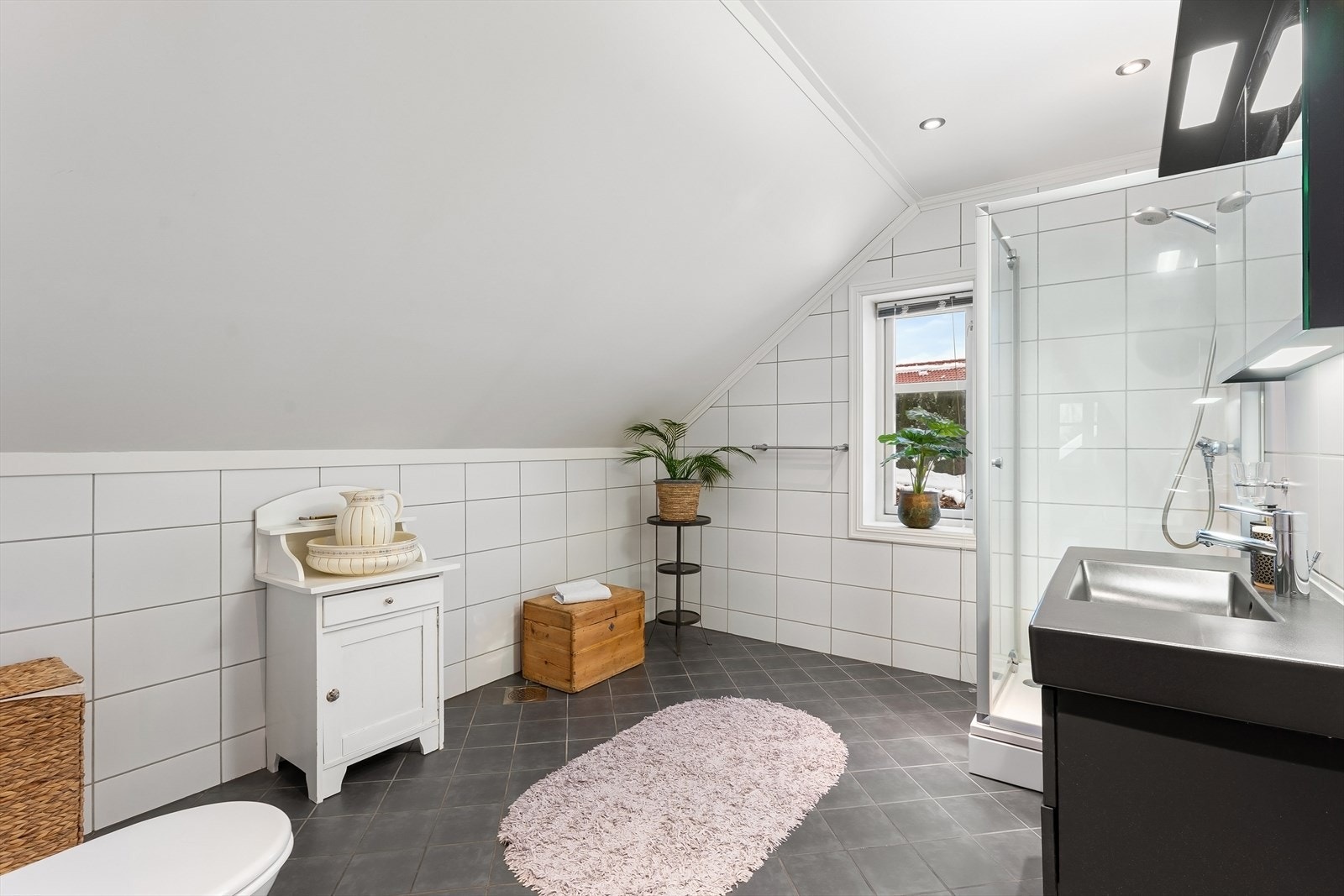 Badet har innredning med nedfelt servant, speilskap med lyslist, veggmontert toalett og dusjvegger i glass. Galleribilde