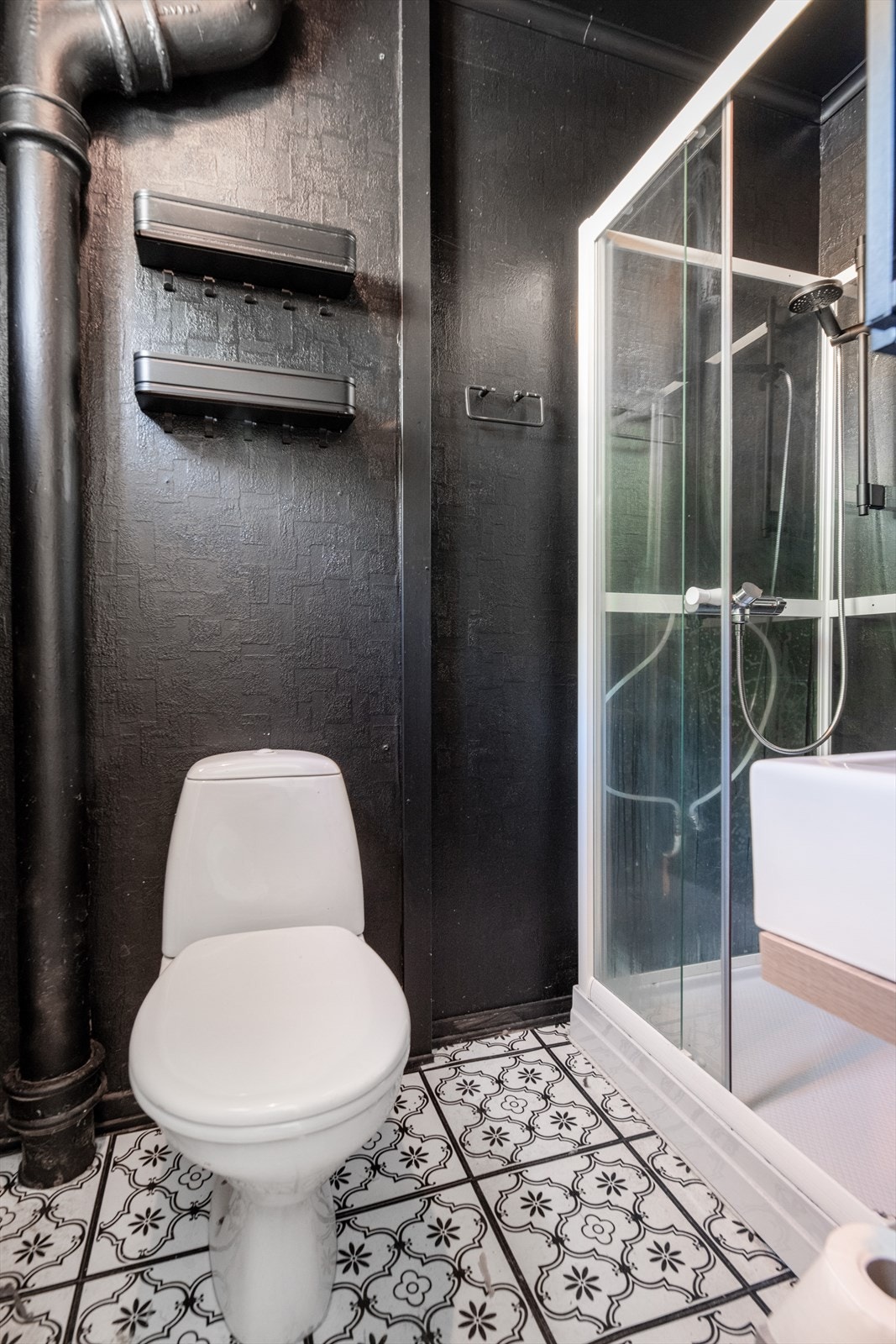 Badet ligger i praktisk tilknytning til entré og inneholder enkel innredning med toppmontert servant, ett greps blandebatteri, dusjkabinett og gulvmontert toalett. Galleribilde