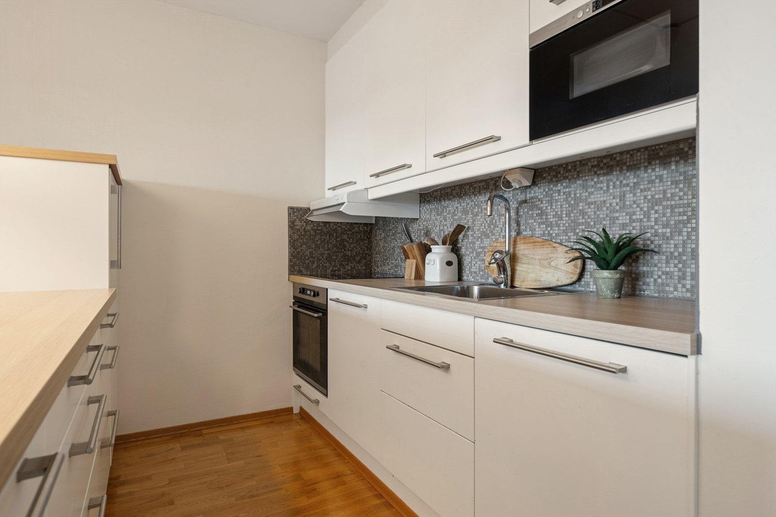 Kjøkkeninnredningen er fra 2014 og har hvite, slette fronter med en laminatbenkeplate. Det er montert fliser på veggen mellom benk og overskap. Galleribilde