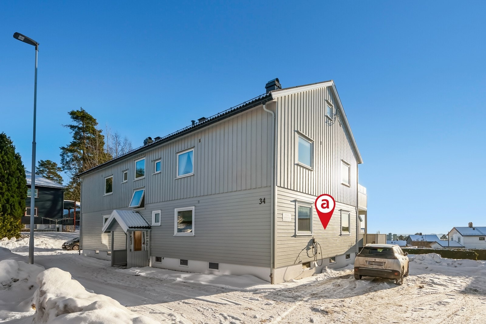 Fasade inngangaparti. Leiligheten har biloppstillingsplass på borettslagets tomt. Det er installert elbil-lader. Galleribilde