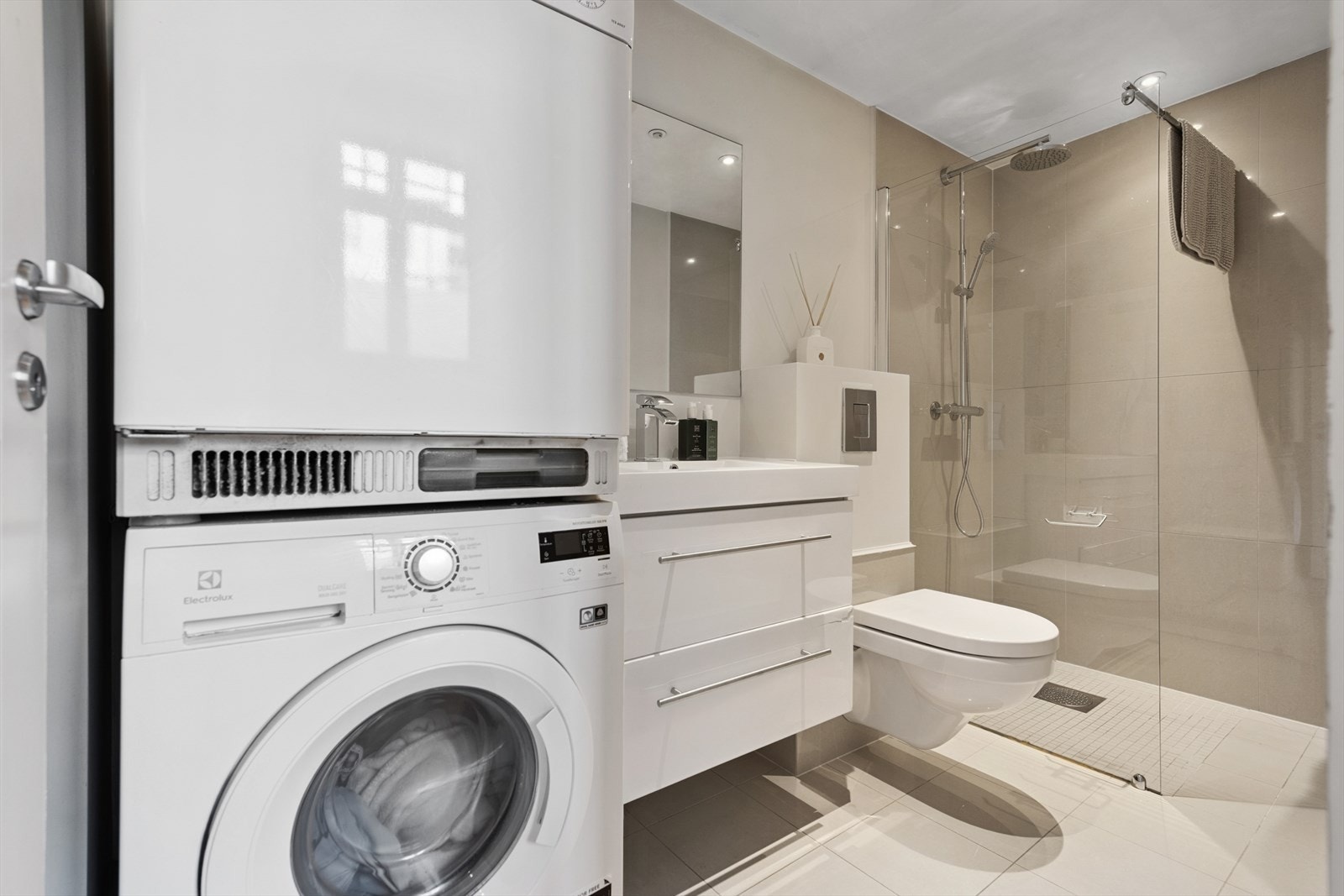 Flislagt bad med praktisk opplegg for vaskesøyle, som utnytter plassen godt Galleribilde