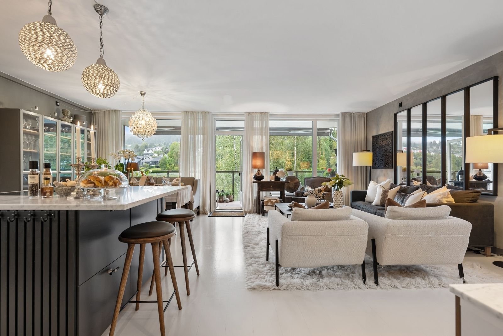 Vegetasjon langs vannet bringer naturen inn i den flotte leiligheten. Her er stuen sett fra gangen, og en del av kjøkkenøya ses i forkant. Benkeplate med overheng, noe som gir god plass til plass for 2 personer. Galleribilde