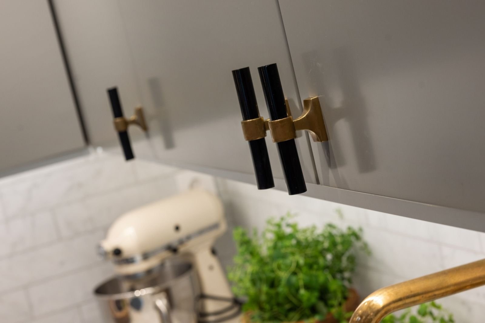 Detaljbilde fra kjøkken med kjøkkenkran fra Tapwell i messing, og håndtak på skuffer og skap i sort og messing. Galleribilde