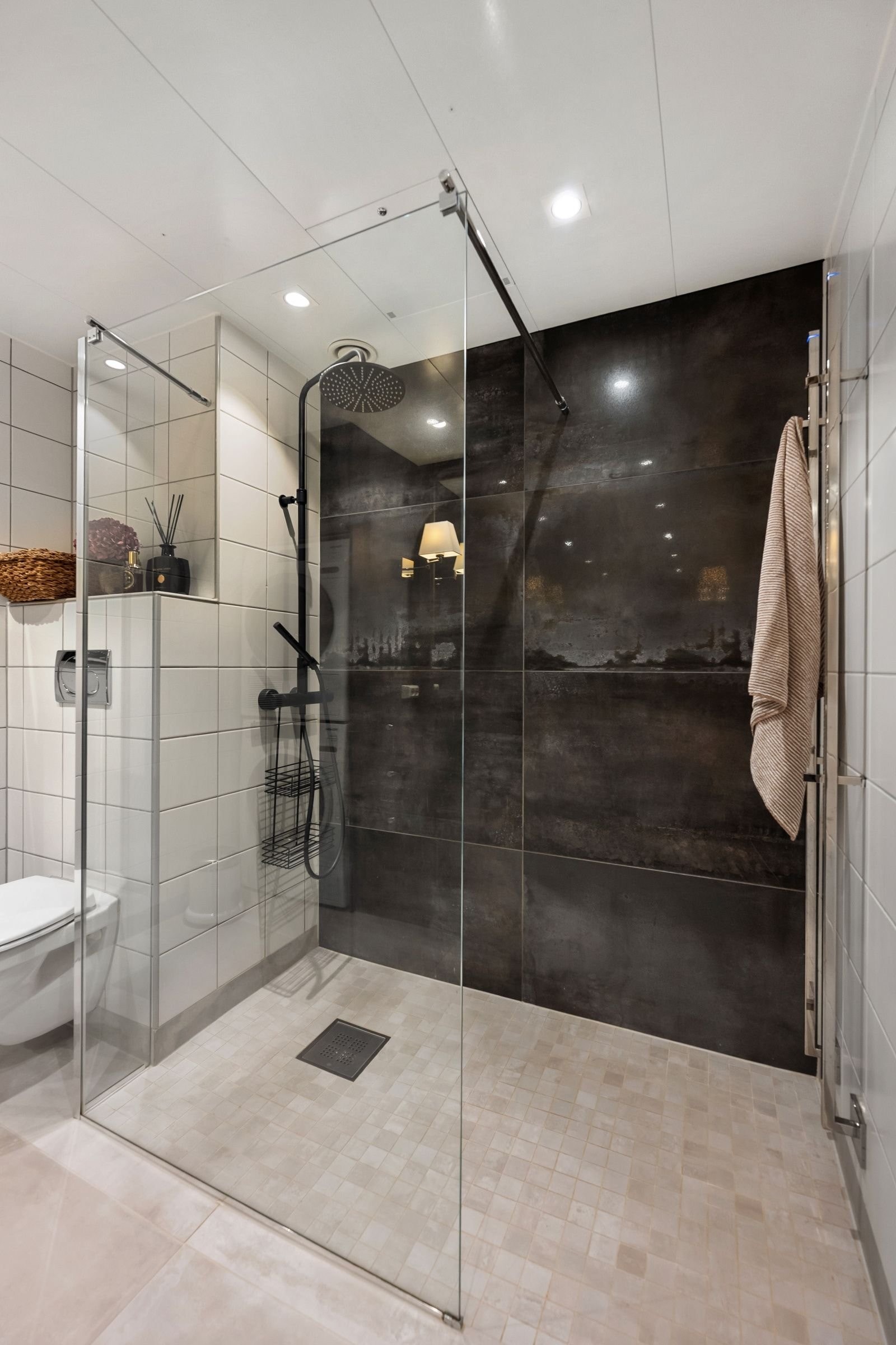 Det er lagt flis på flis på gulv og en fondvegg. Dusjsonen har mosaikkfliser, men holdt i samme farge som de store flisene på gulvet. Galleribilde