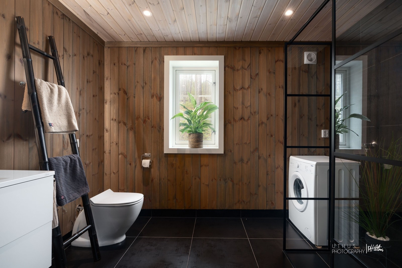 Romslig og delikat baderom med fliser på gulv, panelvegger og vindu som gir naturlig lys Galleribilde