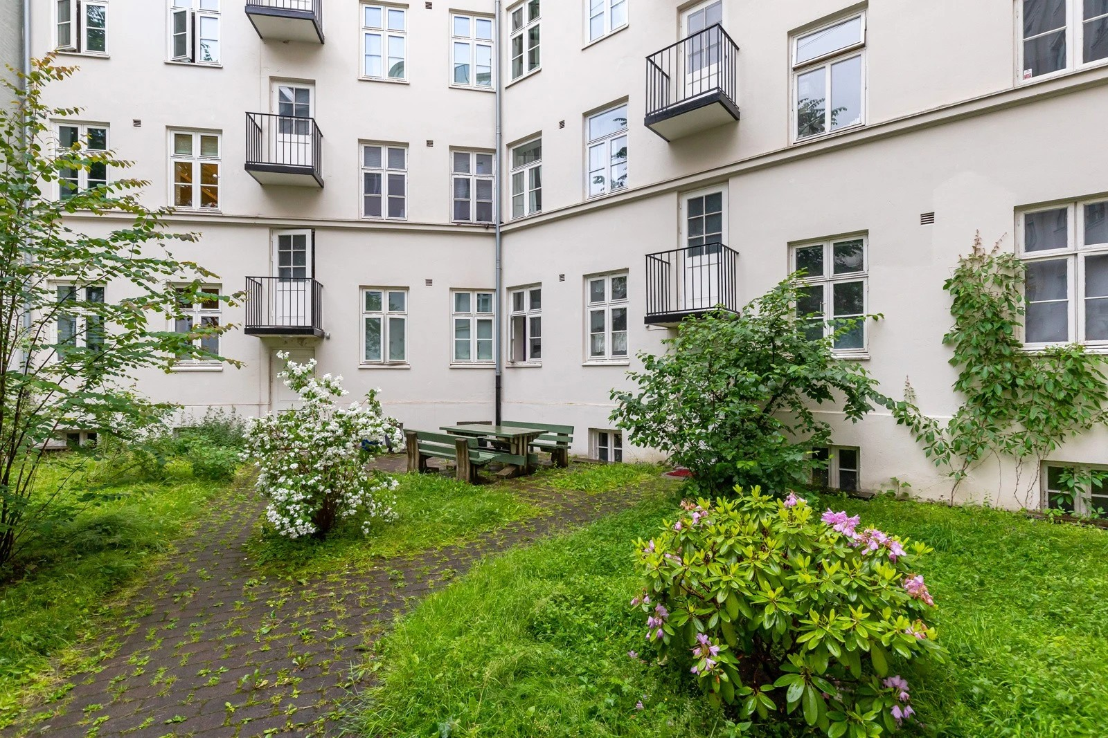 Frodig bakgård med nøye planlagt landskapsdesign. Gårdsrommet er pent opparbeidet, med en myk gressplen som innbyr til avslapning og sosialt samvær. Galleribilde