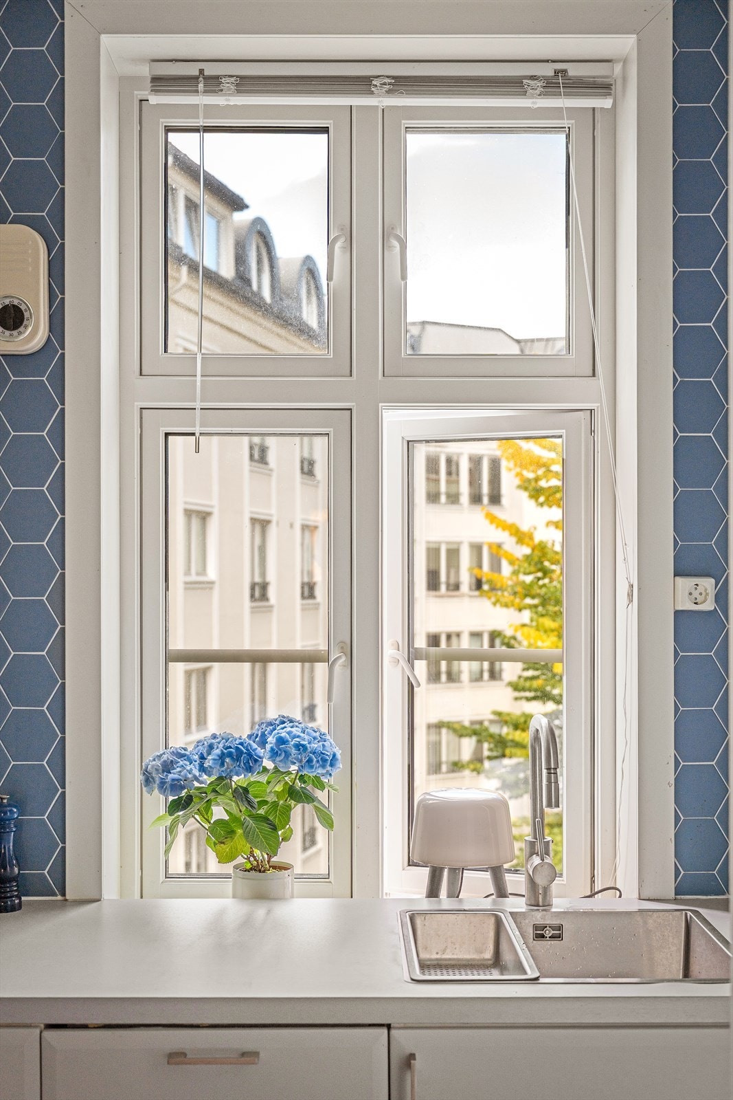 Kjøkken med vindu mot en sjarmerende og frodig bakgård. Galleribilde