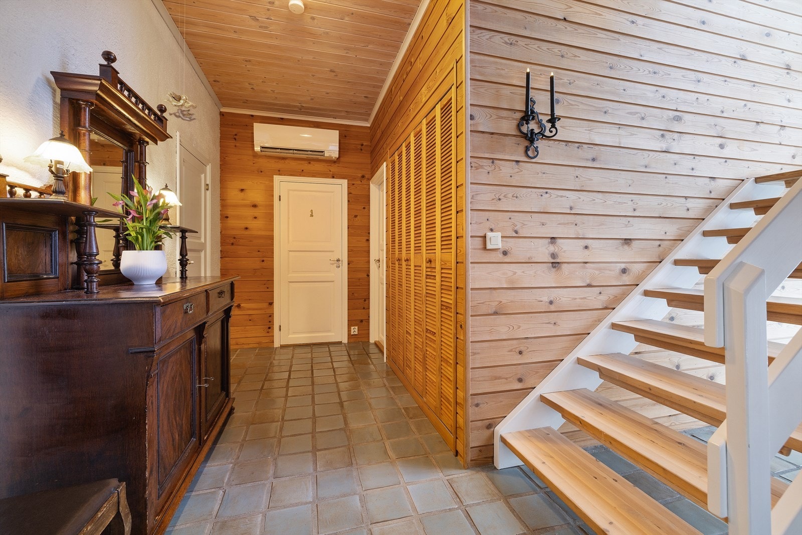 Hallen i første etasje har en lakkert tretrapp som leder opp til boligens hovedetasje. Galleribilde