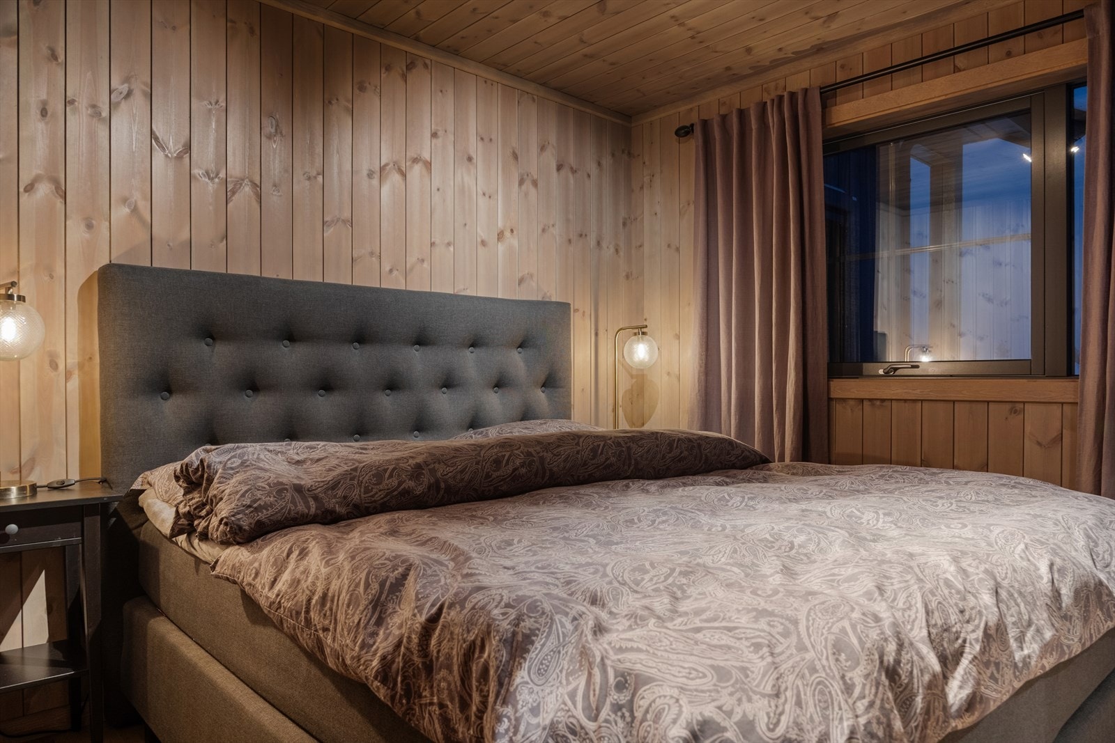 Hyttas tre soverom i 1. etasje byr på en gjennomført og harmonisk stil som skaper en varm og avslappende atmosfære. Alle rommene har parkettgulv som gir en solid og innbydende base, samt beiset panel på vegger og himling som fremhever hyttas lune karakter Galleribilde