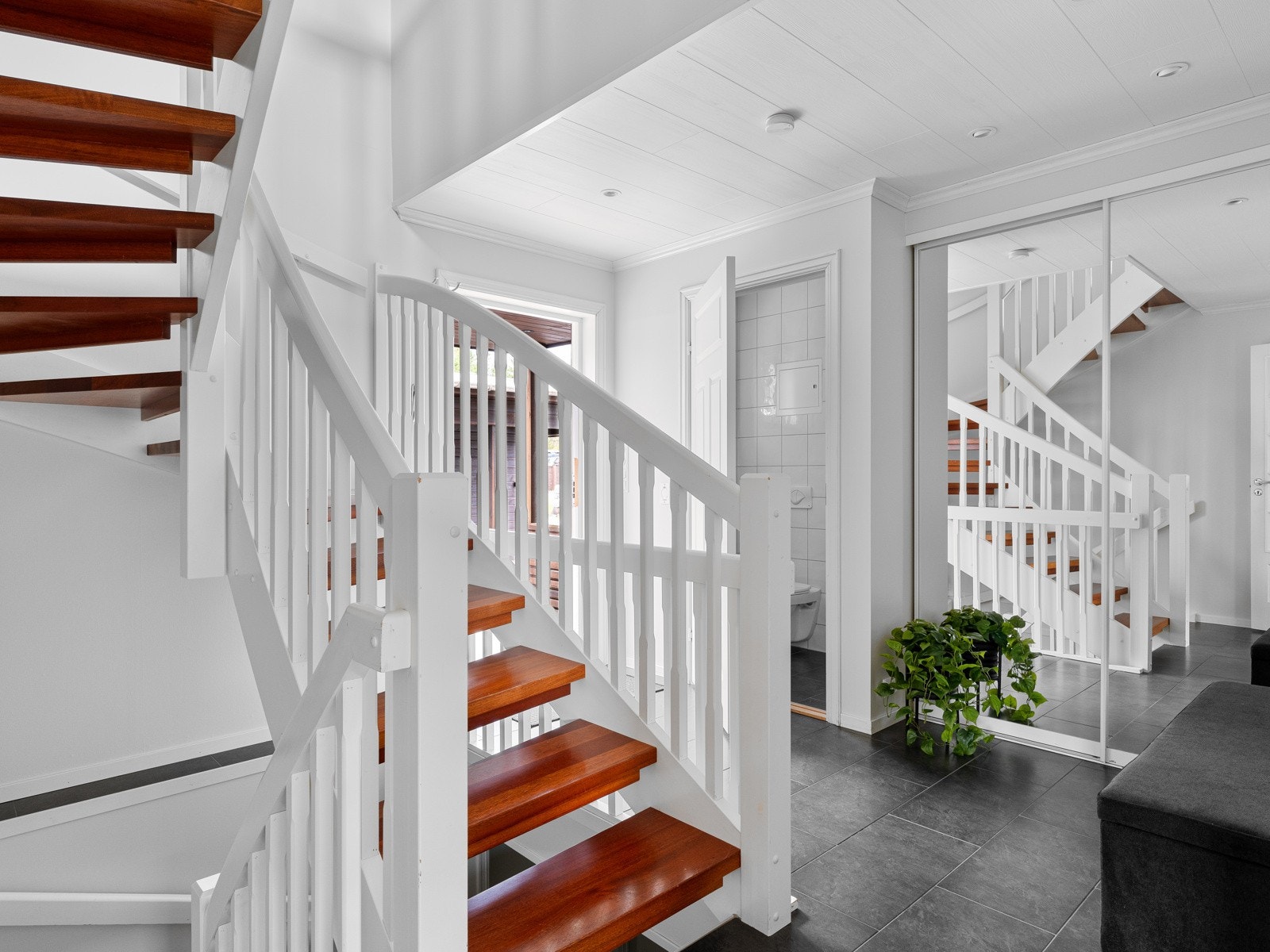 Fin velkomst i romslig, flislagt entré med åpen trappeløsning og praktisk skyvedørsgarderobe. Galleribilde