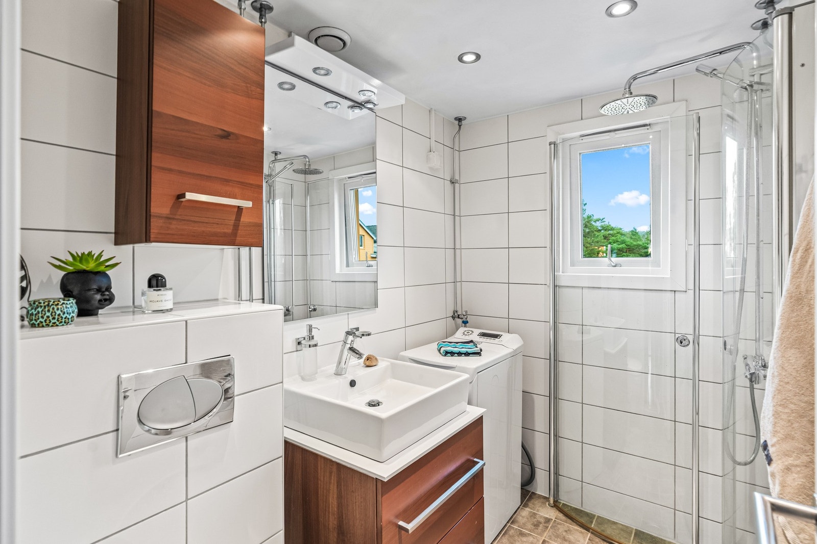 Badet har vegghengt servantinnredning med ovenpåliggende servant, vegghengt toalett, downlights i himling og opplegg for vaskemaskin. Galleribilde