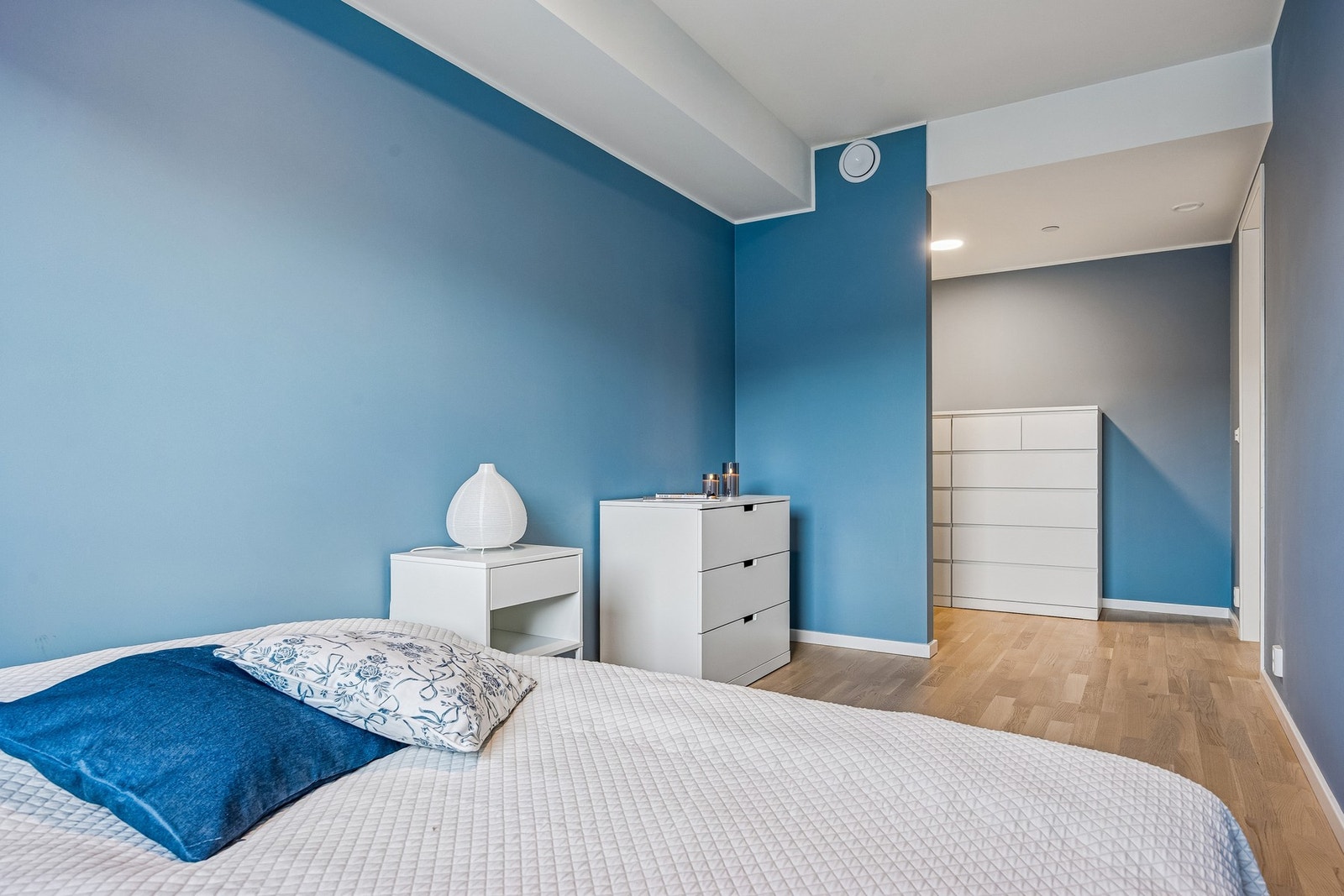 De lyse overflatene og moderne fargevalg bidrar til et stilrent uttrykk, og gjør soverommet til et komfortabelt og avslappende rom egnet for både hvile og oppbevaring. Galleribilde