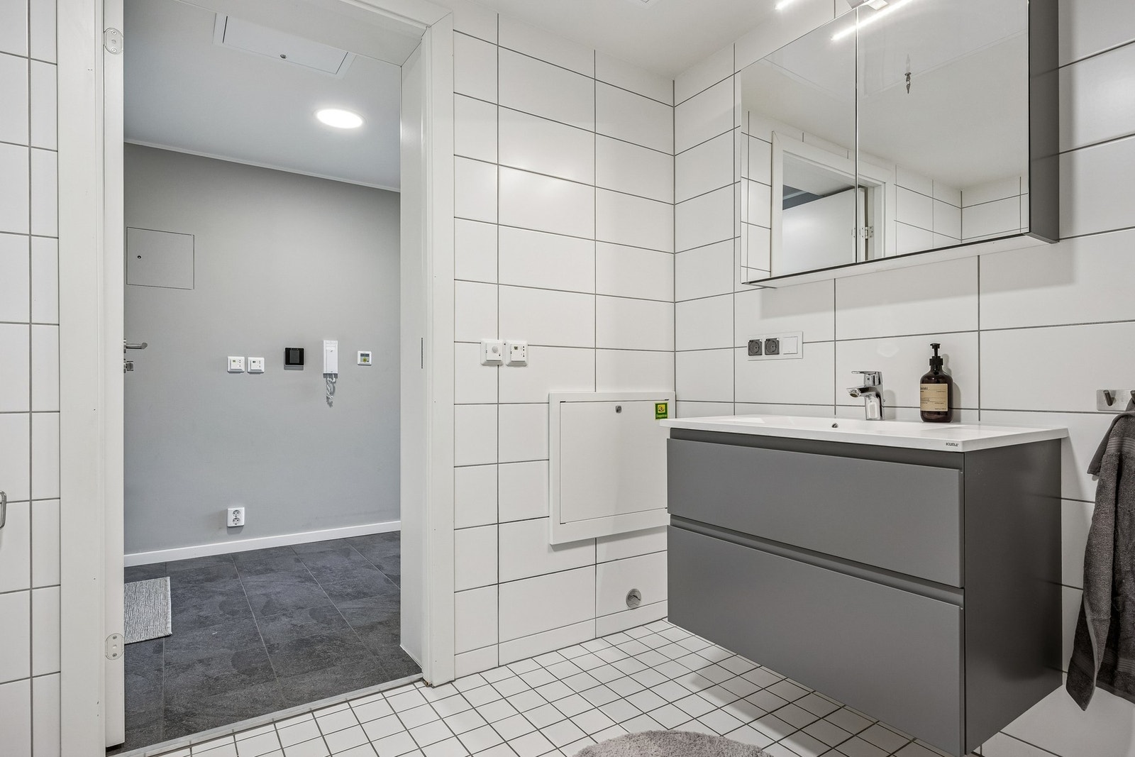 Her finner man vegghengt toalett, servantinnredning med ovenpåliggende servant, speilskap med overlys og stikkontakt, samt dusjhjørne med dører og både hånddusj og regndusj. Galleribilde