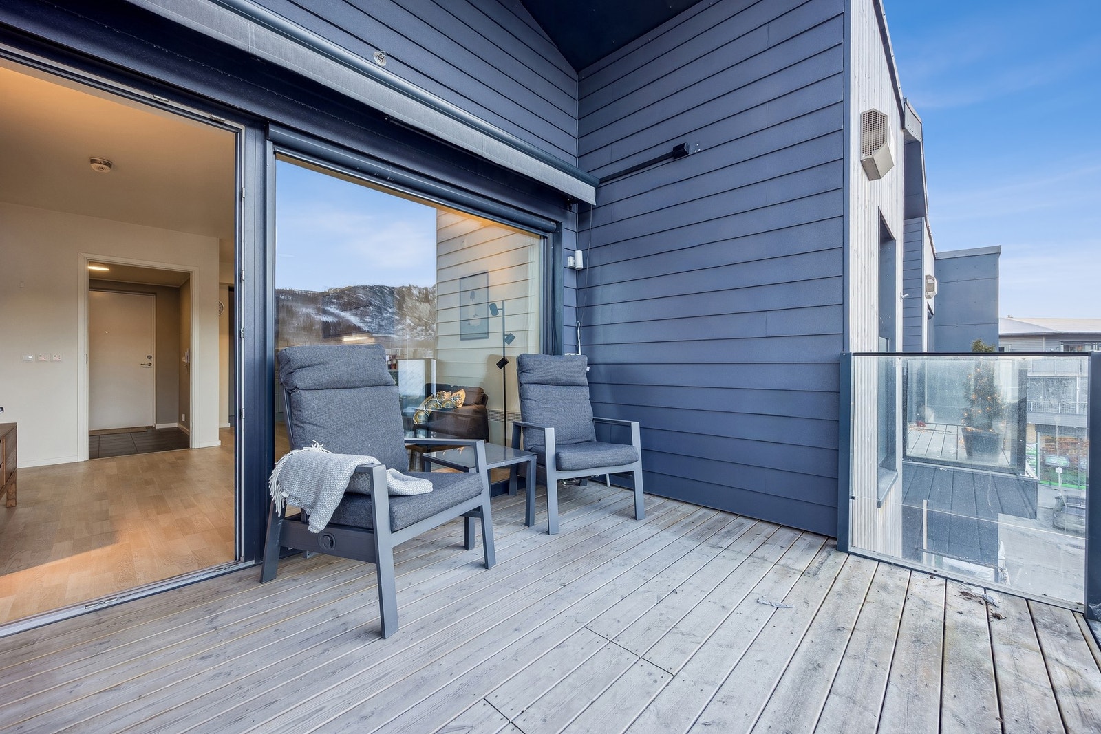 Balkongen fungerer som en naturlig forlengelse av stuen og gir fine rammer for avslapning og sosiale sammenkomster i sommerhalvåret. Her kan man nyte gode solforhold og en åpen utsikt mot nærområdet og omkringliggende bebyggelse, med glimt av sjø og lands Galleribilde