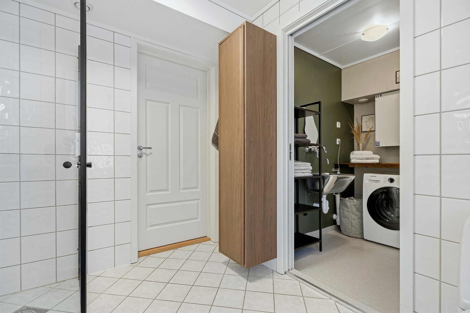 Et vegghengt skap gir den ekstra skapplassen en trenger i hverdagen, samt at det er skyvedør inn til vaskerom med ekstra oppbevaringsplass Galleribilde