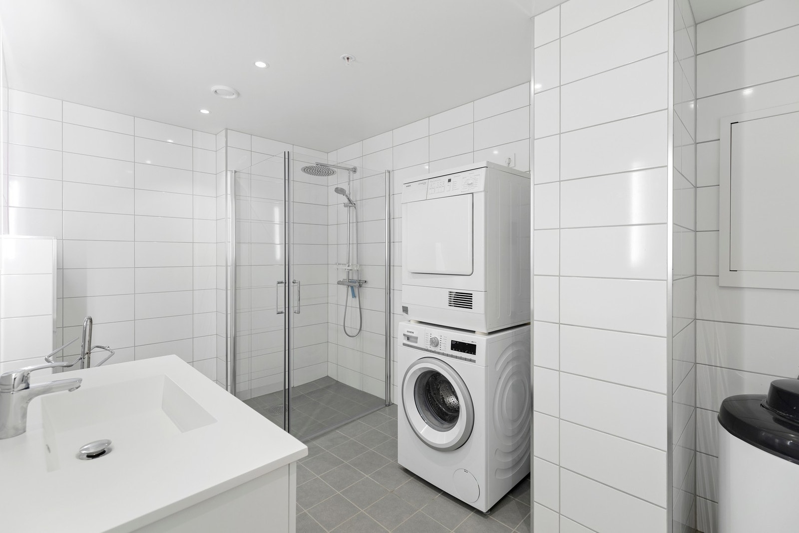 Kombinert bad og vaskerom med fliset gulvoverflate, og fliskledde vegger Galleribilde