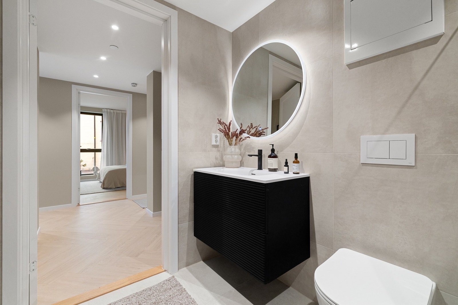 Dusjhjørne med glassvegger og matt sorte armaturer. Vegghengt toalett og skjult sisterne for et rent, moderne uttrykk. Galleribilde