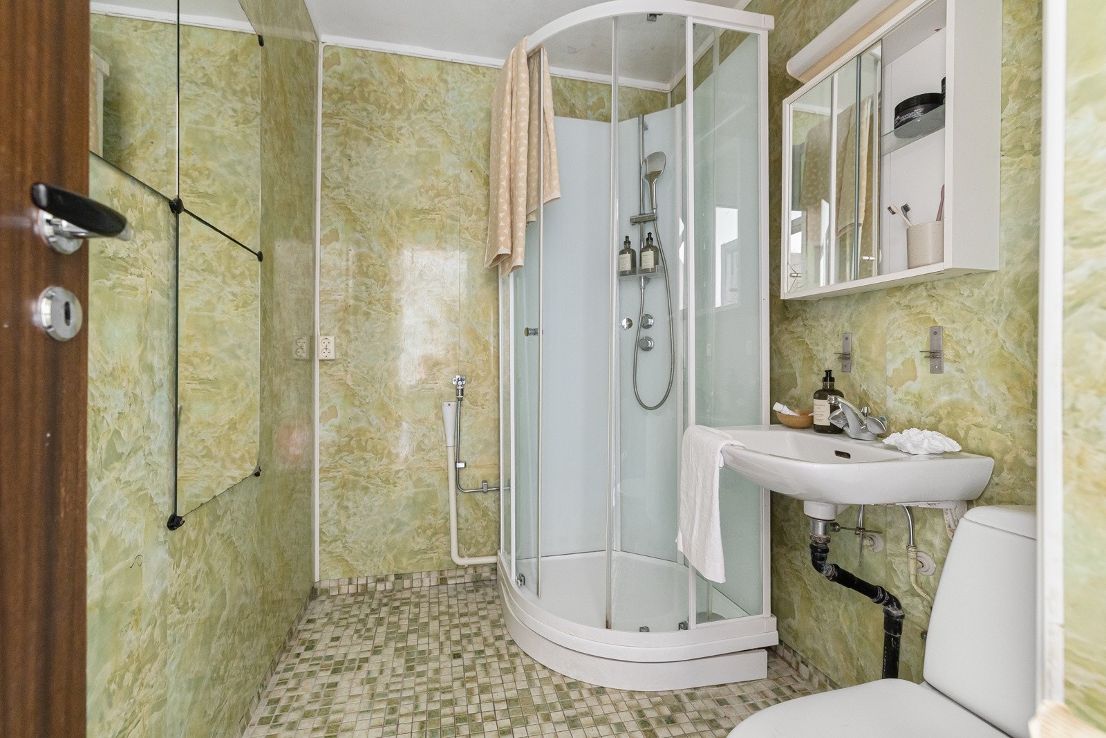 Bad innredet med servant, speilskap, dusjkabinett, toalett, samt opplegg for vaskemaskin. Galleribilde