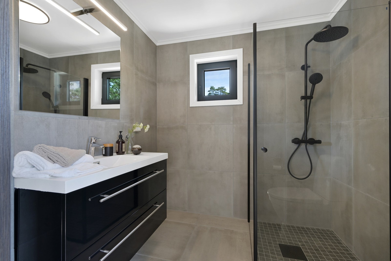 Flislagt bad med elektriske varmekabler, nedfelt servant, gulvmontert toalett, dusjvegger/hjørne og opplegg for vaskemaskin. Galleribilde