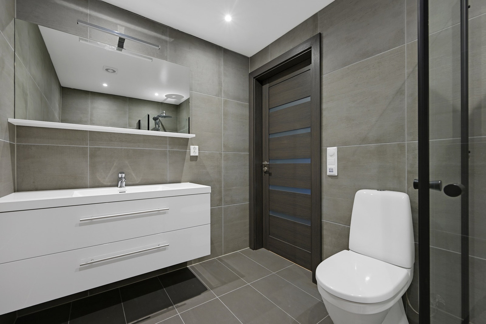 Badet ble renovert i 2023 og er innredet med nedfelt servant, veggmontert toalett, dusjvegger/hjørne og opplegg for vaskemaskin. Galleribilde