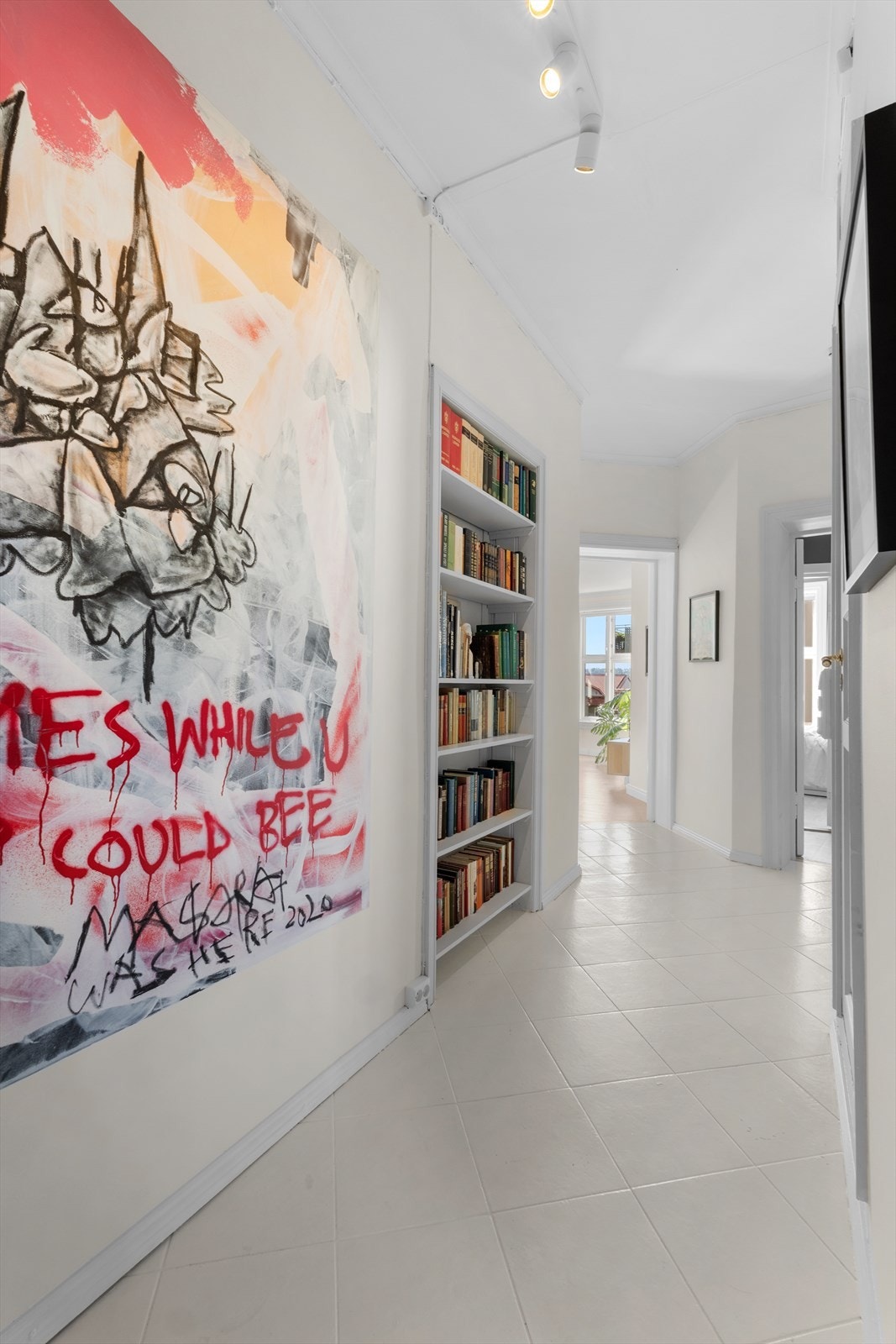 Gang med lyse fliser på gulv og ellers lyse overflater Galleribilde