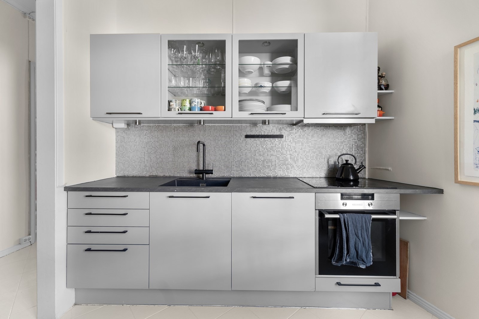 Kjøkkeninnredning med glatte fronter, flislagt gulv og godt med skuff -og skapplass Galleribilde