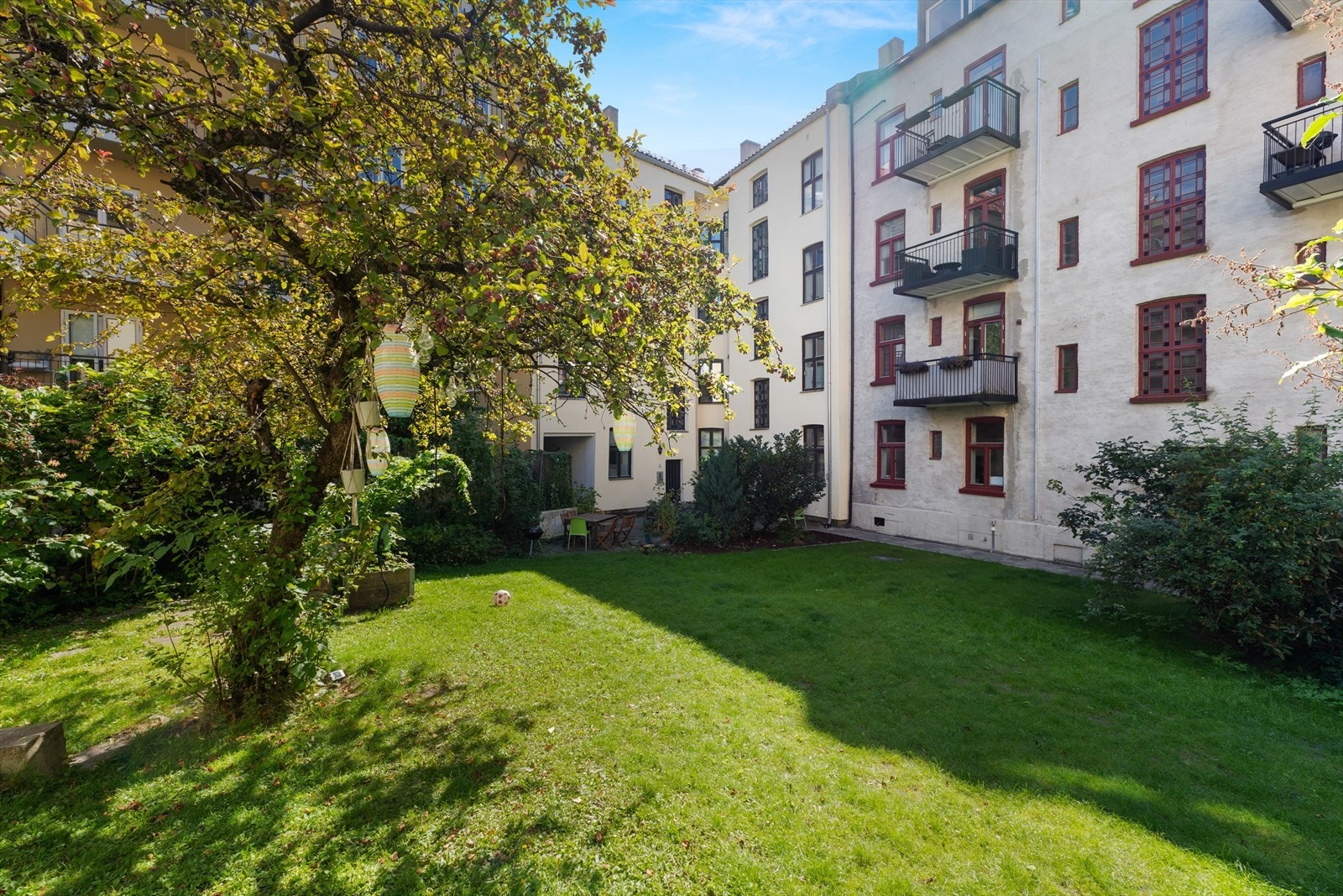 Hyggelig bakgård pent opparbeidet med plen, trær og sittegrupper Galleribilde