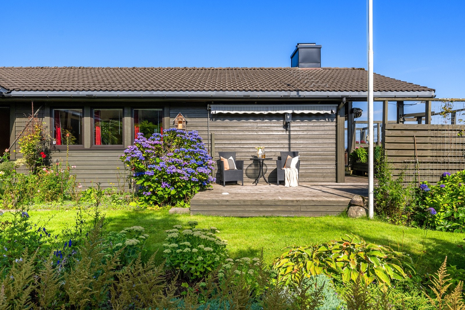 En flaggstang og fine bed langs stien understreker idyllen utendørs. Galleribilde