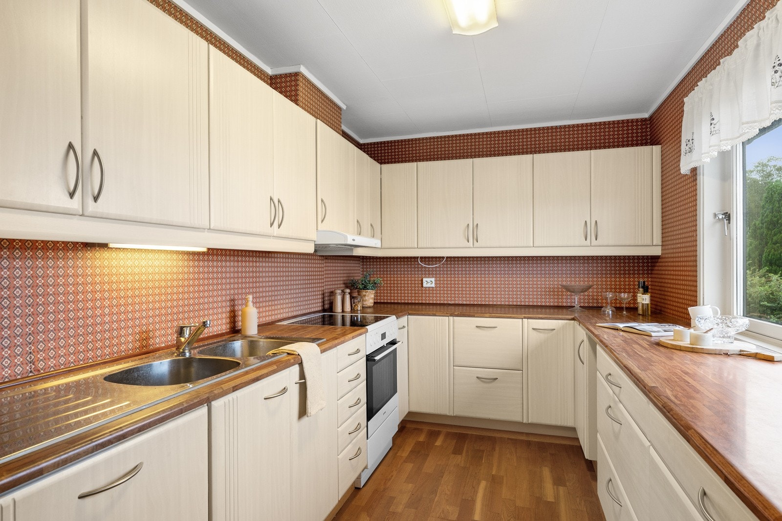 Innredningen er eldre, med lyse, glatte fronter, dobbel oppvaskkum og benkeplate av laminat. Galleribilde