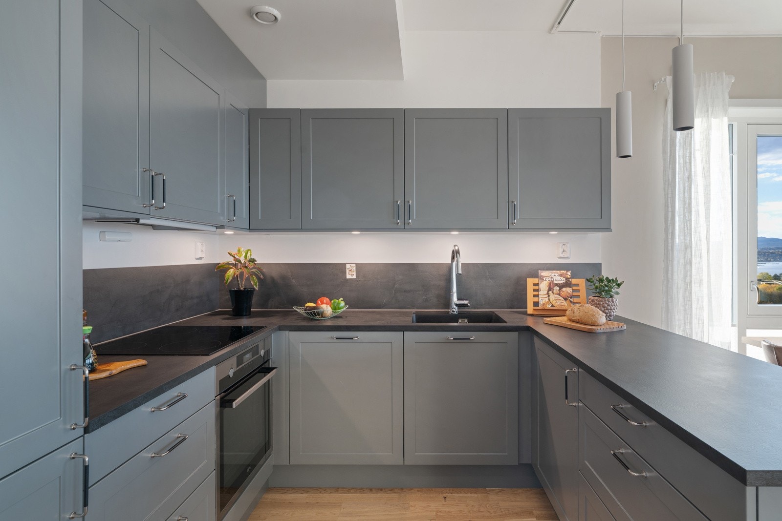 Kjøkkenet er i en grå farge med svart benkeplate. Galleribilde