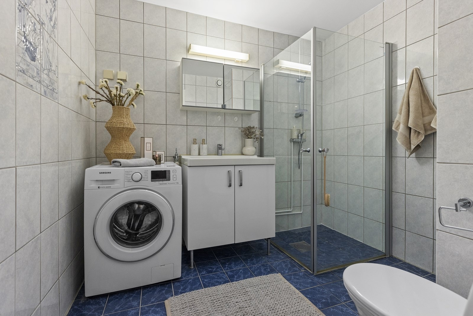 Flislagt bad fra byggeåret. Her er det dusjhjørne med skjermvegger i glass. Badet har behov for modernisering. Galleribilde