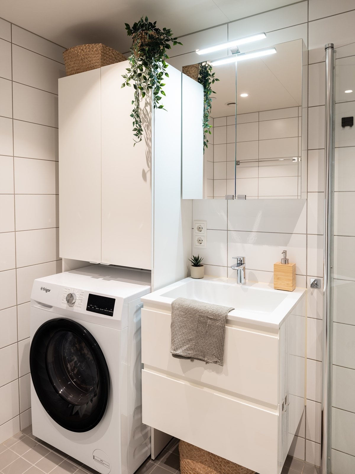 Badet byr på servant, servantskap, innfellbare dusjsdører, veggmontert wc og opplegg for vaskemaskin. Galleribilde