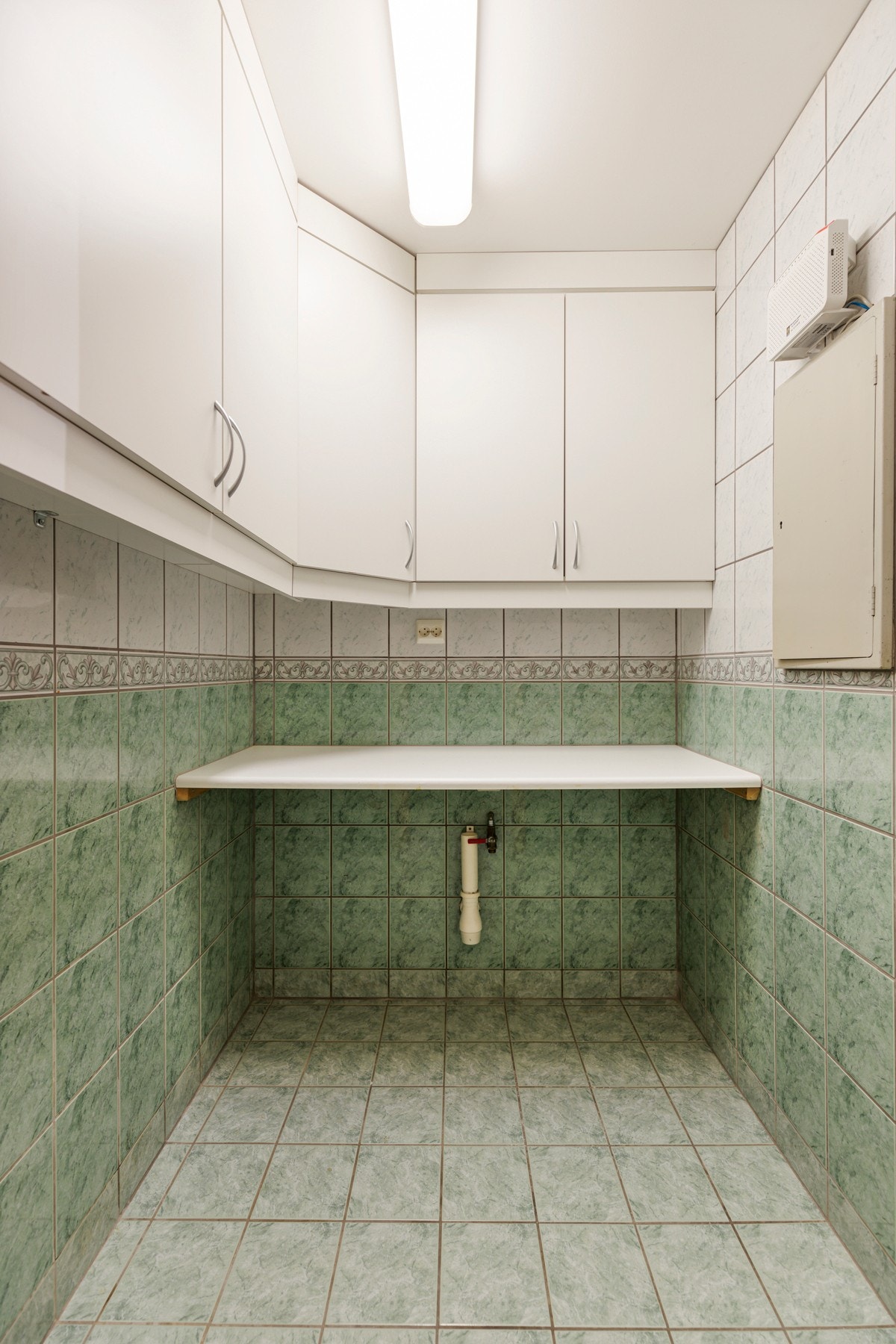 Tilstøtende finner man vaskerommet med takhøye overskap, benkeplate og opplegg for vaskemaskin Galleribilde