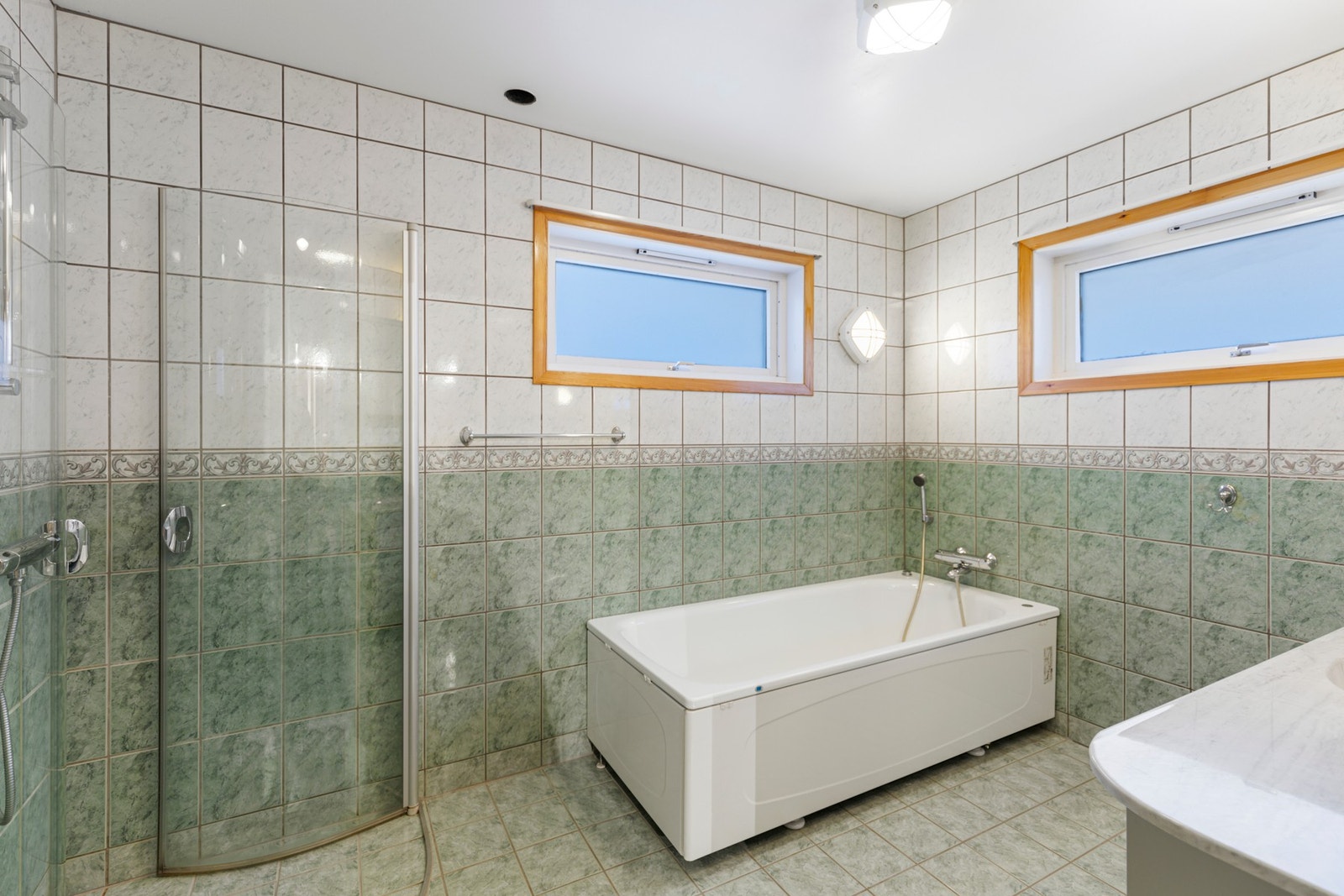 samt badekar, toalett, integrete veggskap og åpen dusjnisje med glassdører Galleribilde