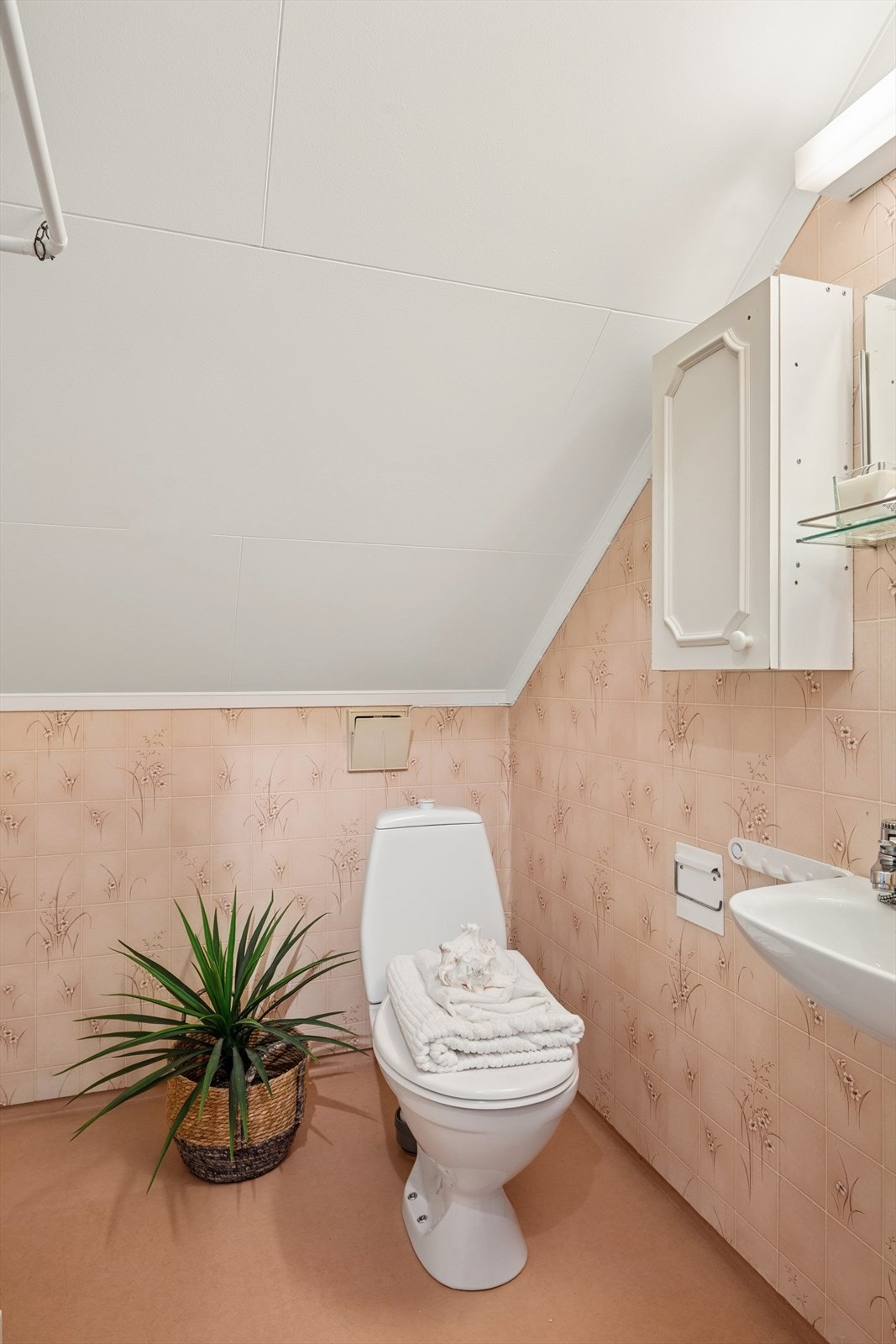 Badet i 2. etasje har tapet på vegger og belegg på gulv, og er utstyrt med toalett, servant, speil og dusj. Galleribilde