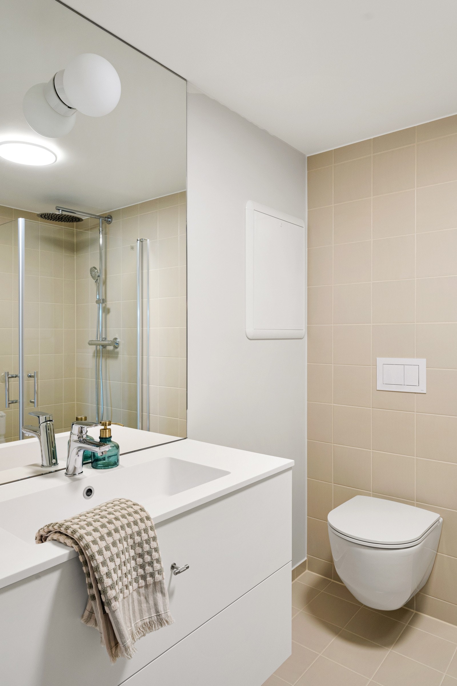 Baderomsinnredningen har hvite fronter og består av en heldekkende servant på en skuffeseksjon og et stort speil med god belysning. Galleribilde