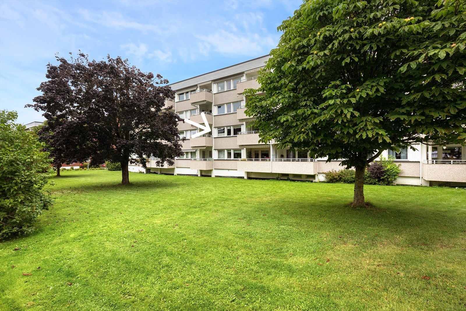 Leiligheten ligger i byggets 2.etasje (markert med pil) med hyggelig utsyn mot borettslagets pent og velholdte tomt Galleribilde