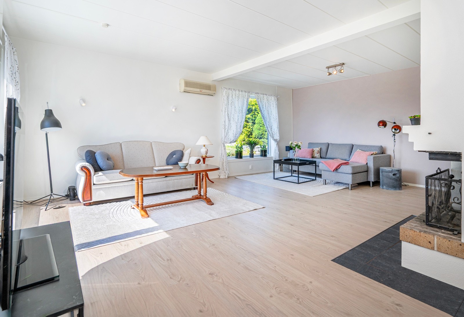 Stuen går i vinkel, noe som gjør den enkel å møbler. Det er en flott peis med pussede overflater - Galleribilde