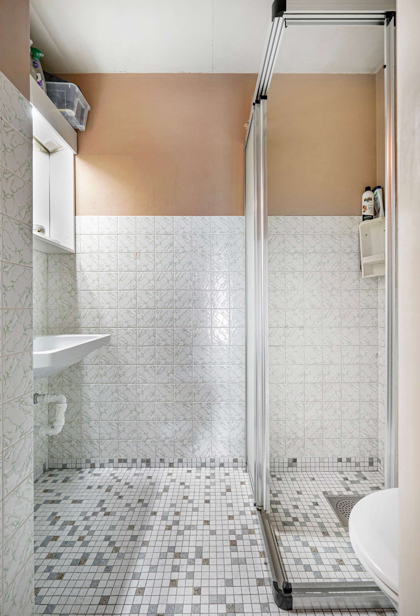 Bad med fliser på gulv og delvis på vegg. Her er dusj, servant og toalett. Galleribilde