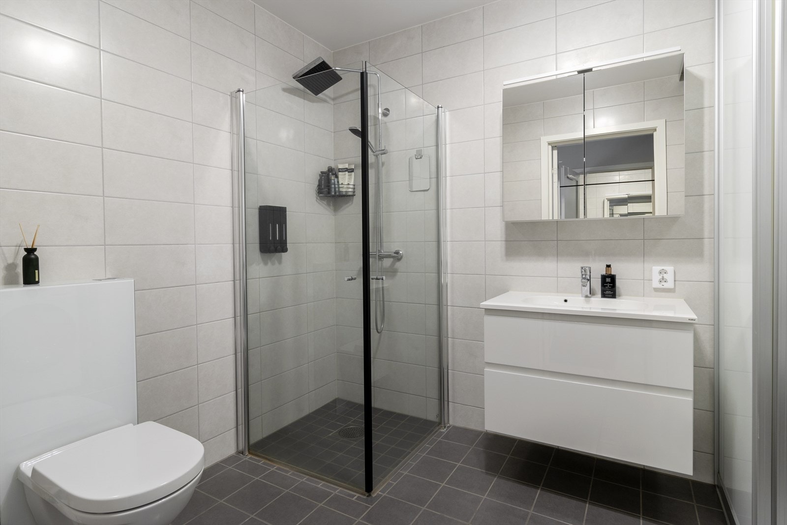 Bad/vaskerom i 1. etasje med stilrene fliser, praktisk innredning og gode oppbevaringsløsninger - perfekt for både daglig bruk og praktisk vaskeromsfunksjon. Galleribilde