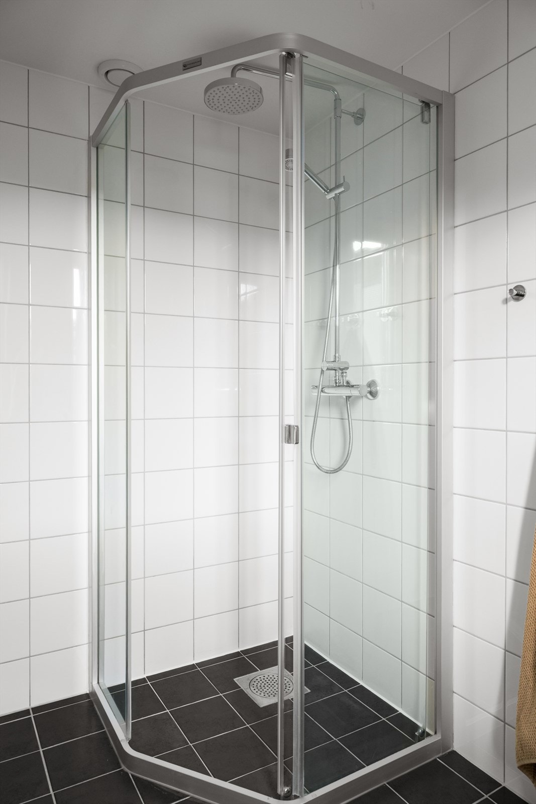 Badet er innredet med vegghengt toalett, dusjhjørne, vask i seksjon og opplegg for vaskemaskin. Galleribilde