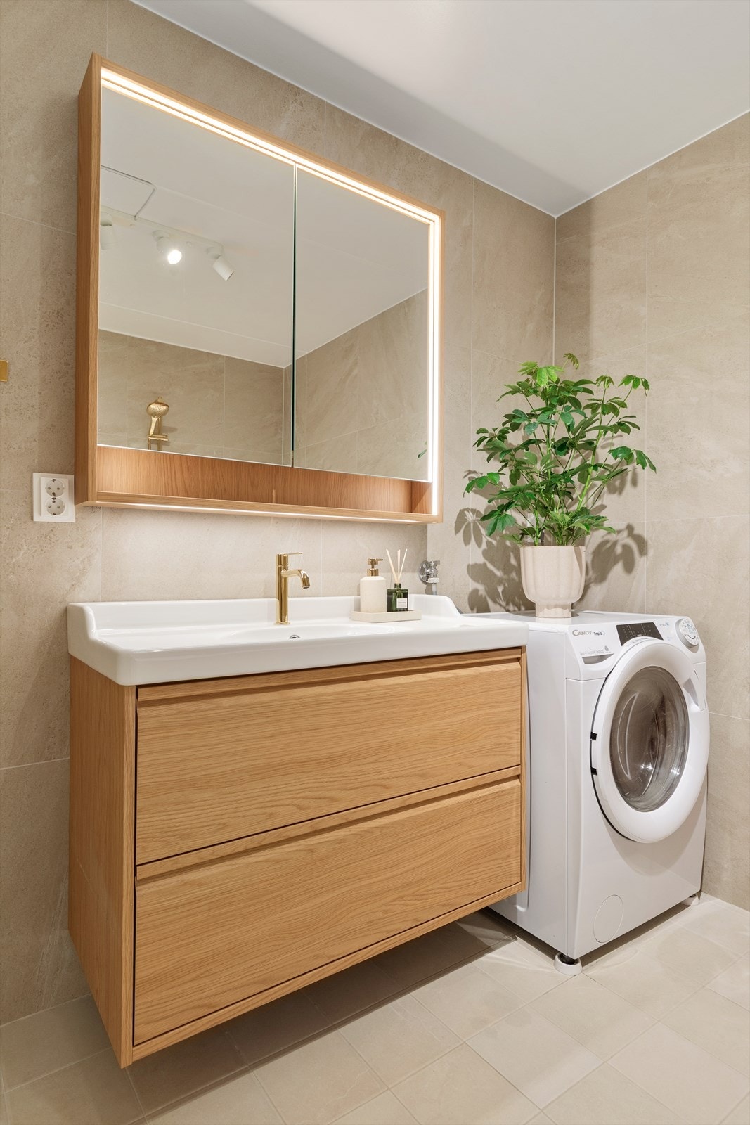 Videre er badet utstyrt med servant med underskap, speilskap med lys, badekar og toalett Galleribilde