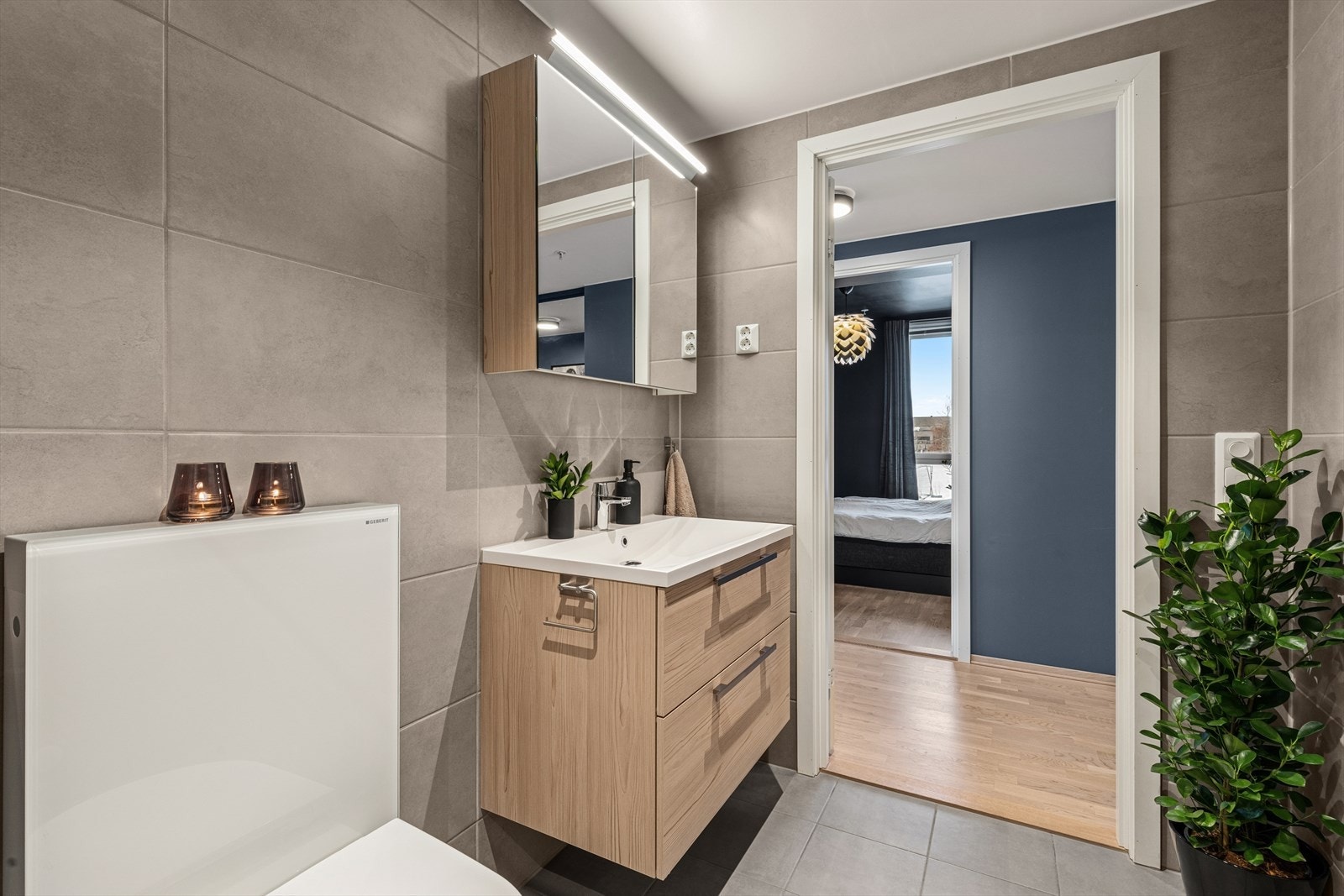 Badet har stilrent baderomsmøbel, speilskap, dusjhjørne med glassvegger og vegghengt toalett. Det er opplegg for vaskemaskin og tørketrommel. Galleribilde