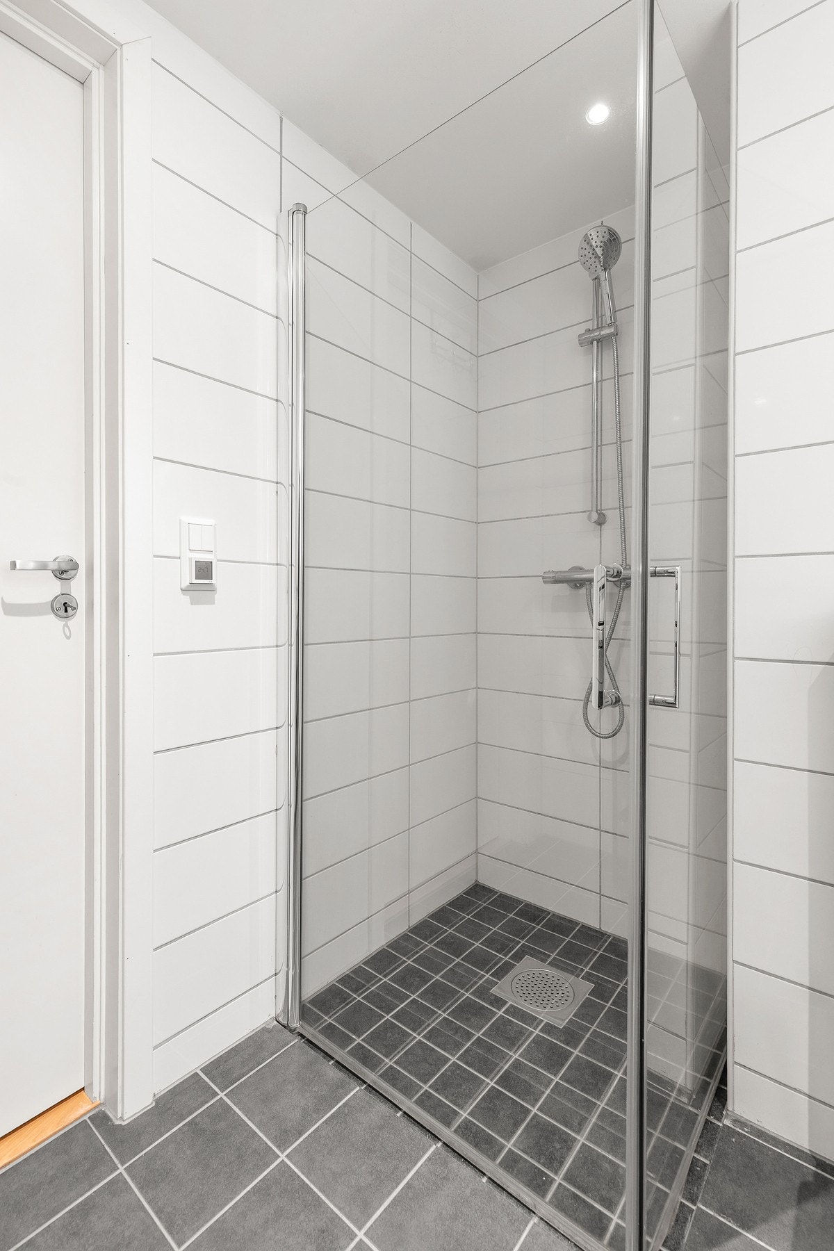 Badet har dusjnisje med innfellbare svingdører i herdet glass Galleribilde