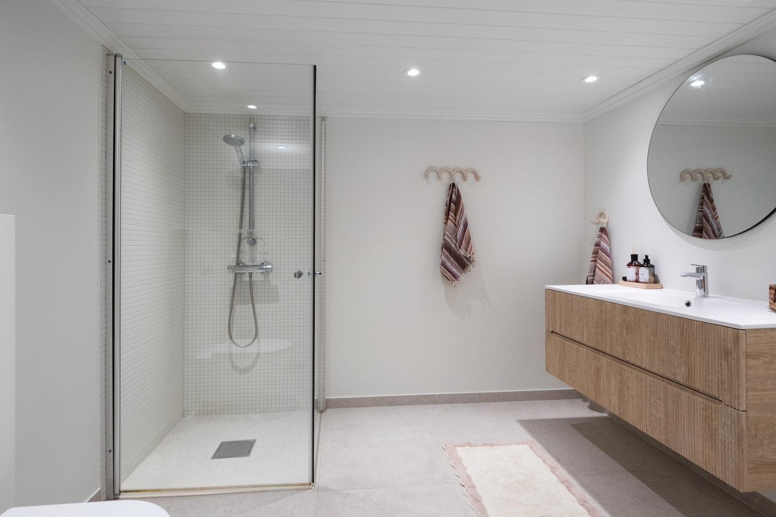 Badet er innredet med enkel vask, dusj med glassdører, veggmontert toalett og opplegg for vaskemaskin. Galleribilde