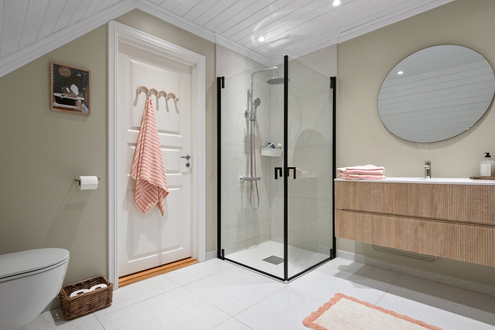 Det er en praktisk innredning med enkel vask, dusj med glassdører og veggmontert toalett. Galleribilde