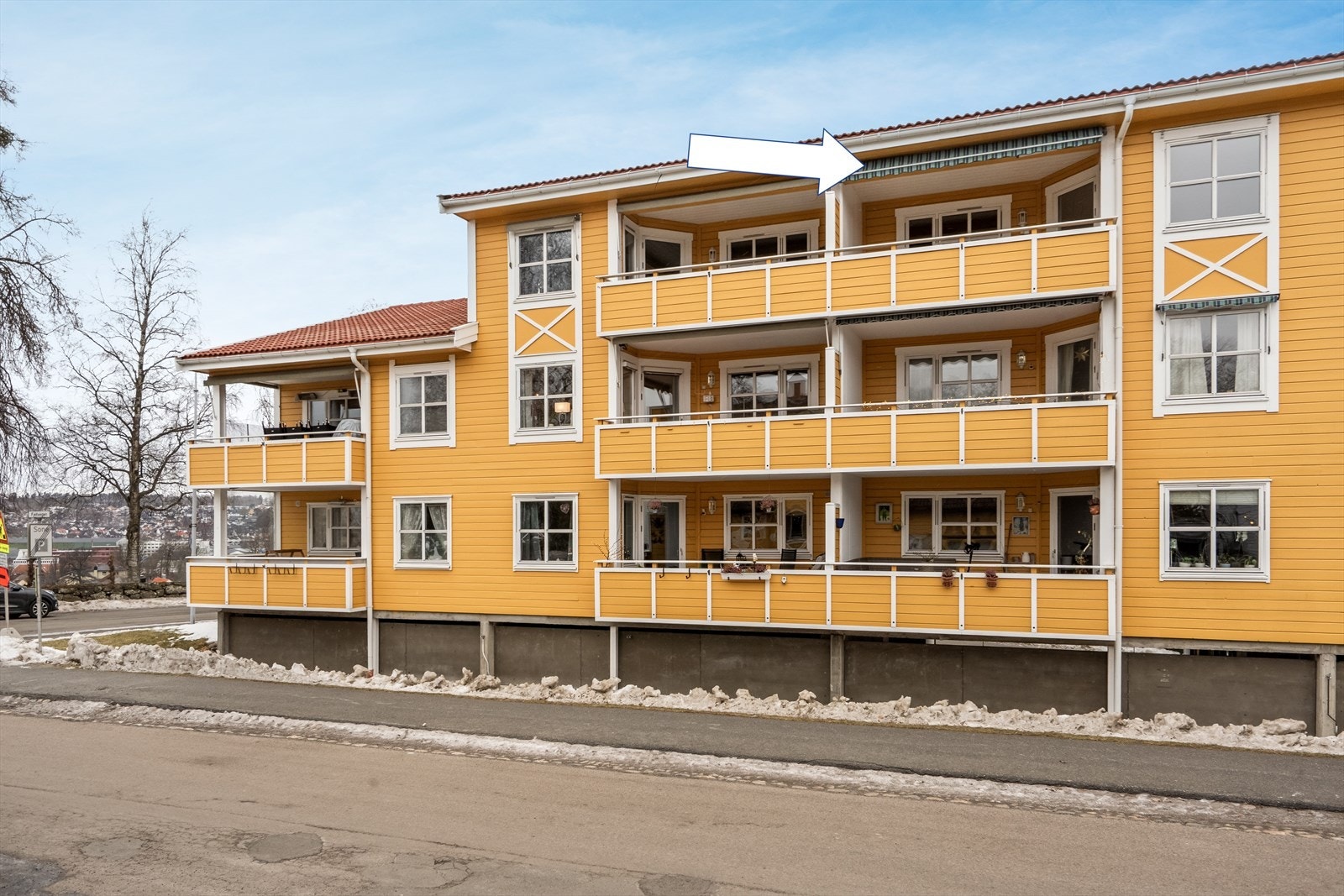 Bygget har en klassisk fasade med gult trepanel og rødt tegltak. Galleribilde