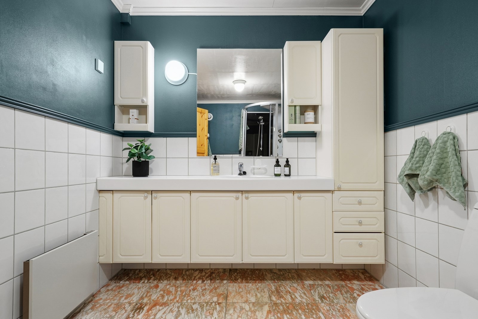 Badet har flislagt gulv med elektriske varmekabler, mens veggene er kledd med en kombinasjon av fliser og våtromsbelegg. Galleribilde