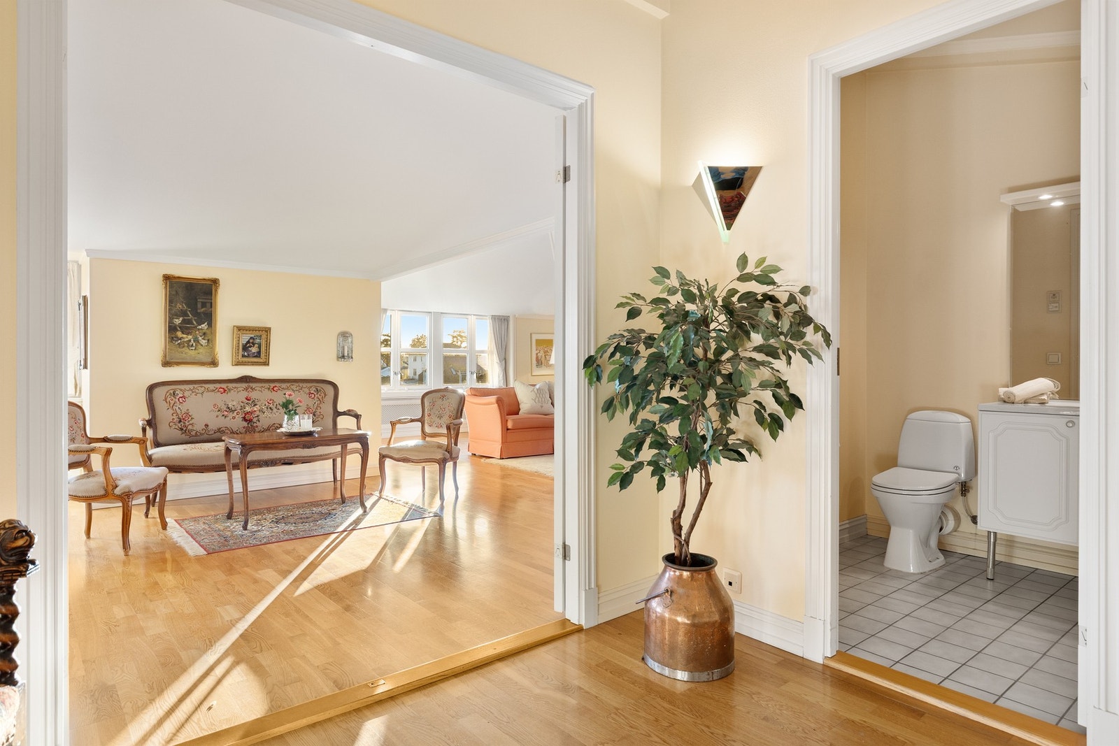 Separat toalettrom med flislagt gulv. Rommet er innredet med vegghengt servantinnredning med hvite profilerte fronter og heldekkende servantbenkeplate med ettgreps blandebatteri, samt gulvmontert toalett. Speil og veggbelysning. Elektrisk avtrekk, med til Galleribilde